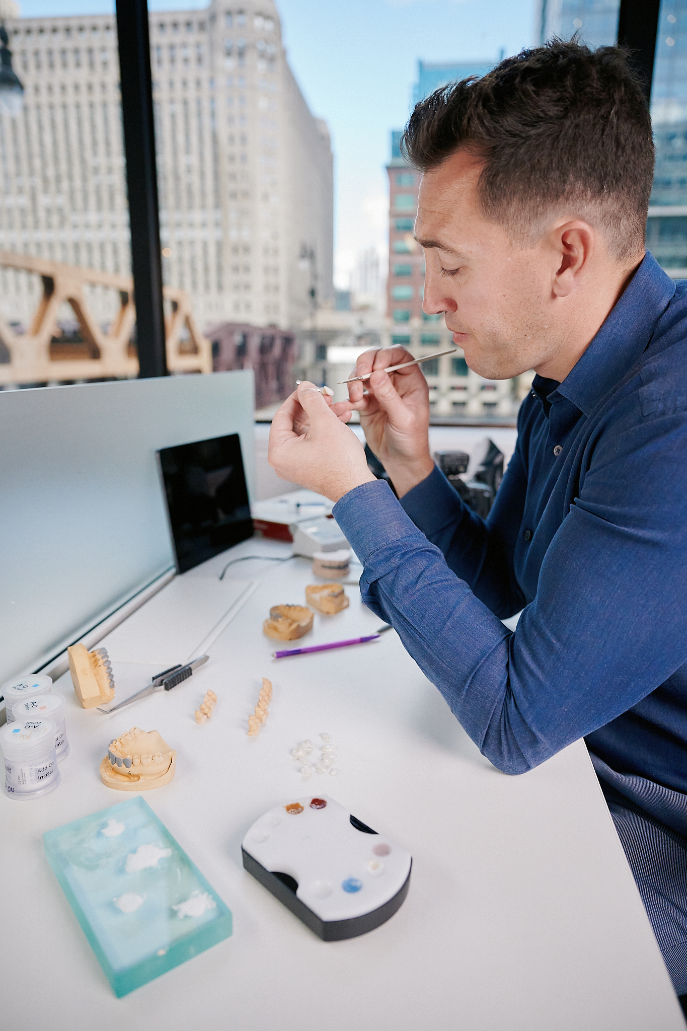 Dr. Schelkopf hand-shading ceramics at his desk, Chicago skyline in view